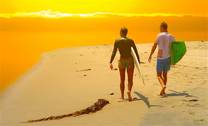 woman in bikini with surfboard on Malibu beach